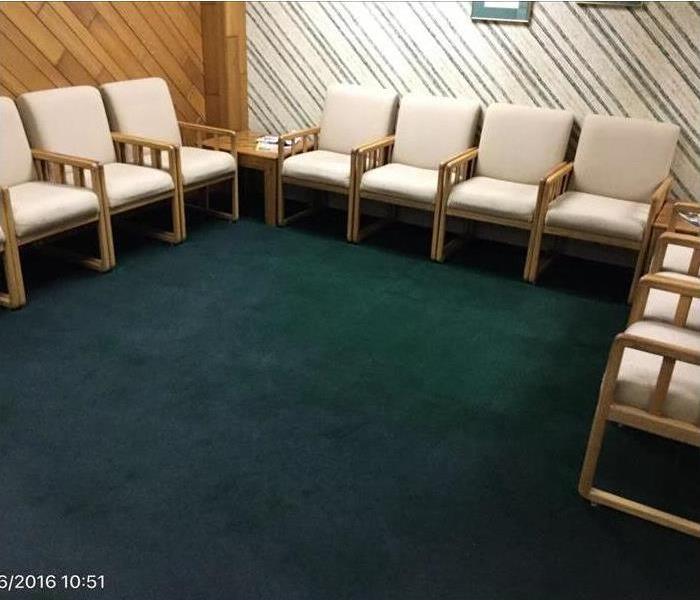Waiting room with dark green carpet with water stains