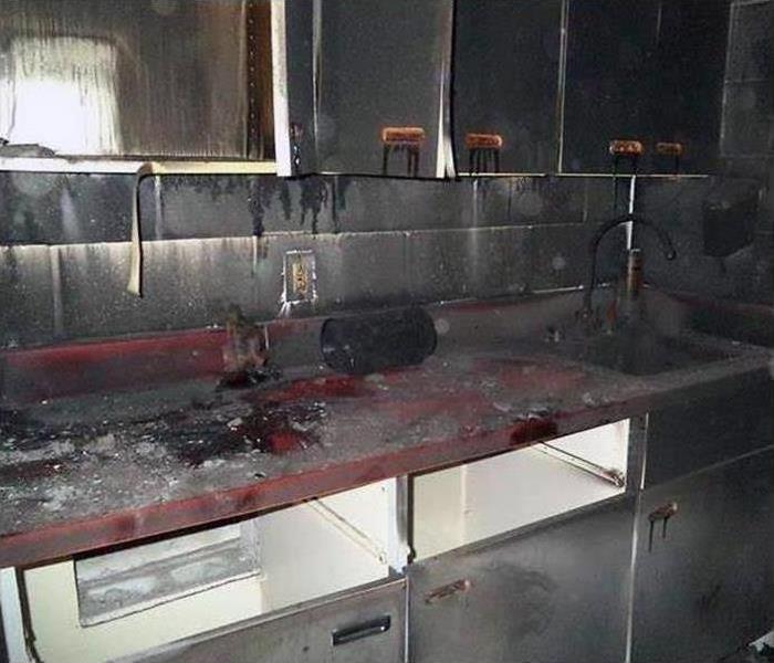 Kitchen sink and cabinets are covered in black soot