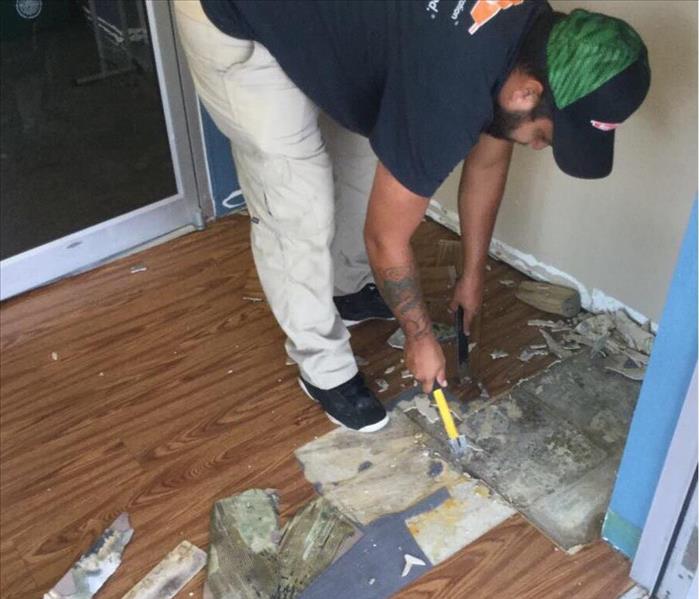 Man tearing out damaged flooring